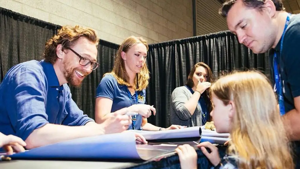 Tom Hiddleston signing autographs at a  convention.