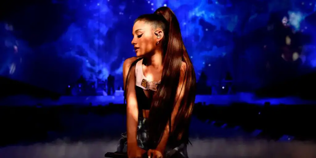 Ariana Grande on her knees with her eyes closed.
